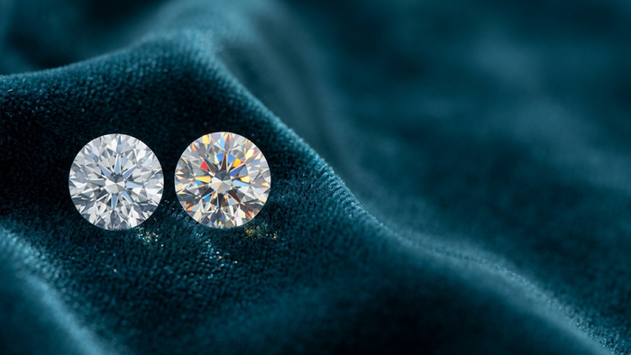 A diamond and a moissanite resting side by side on deep teal velvet