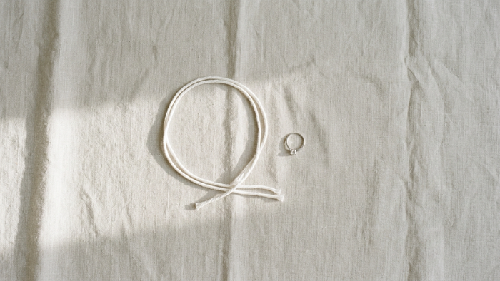 A loop of string and a ring on linen for measuring ring size