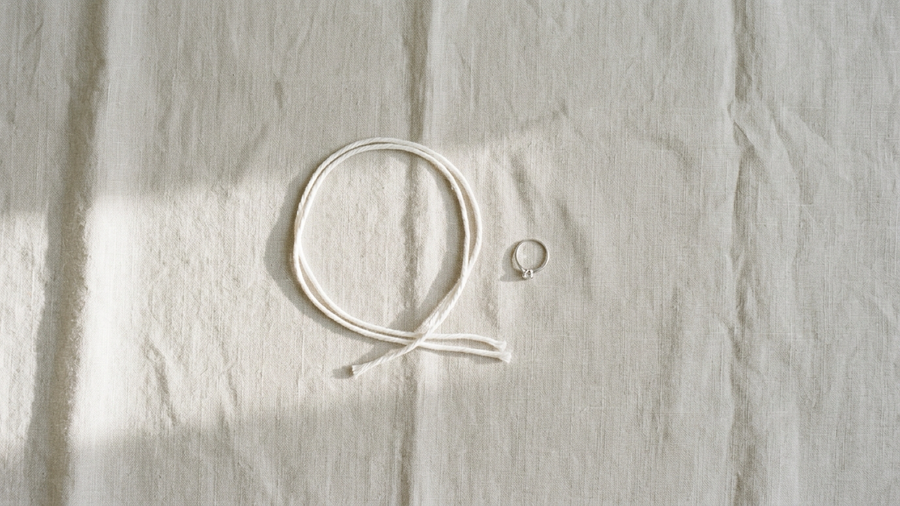 A loop of string and a ring on linen for measuring ring size