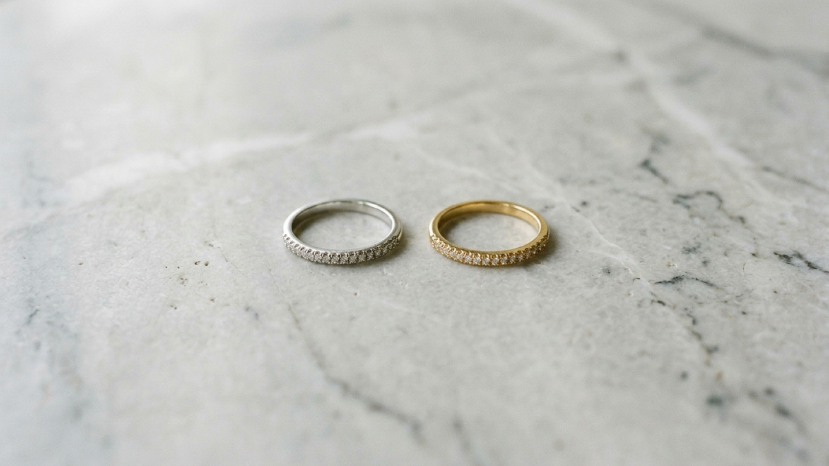 A sterling silver ring and a gold-plated ring side by side on marble