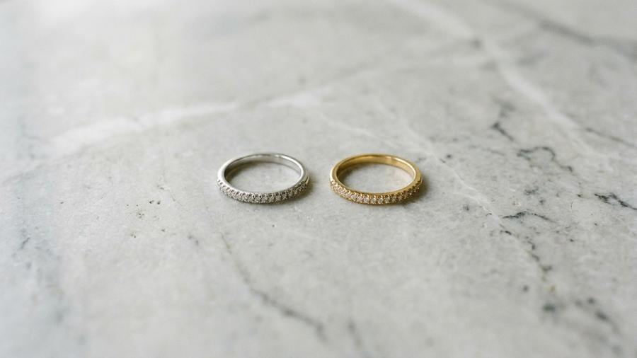 A sterling silver ring and a gold-plated ring side by side on marble