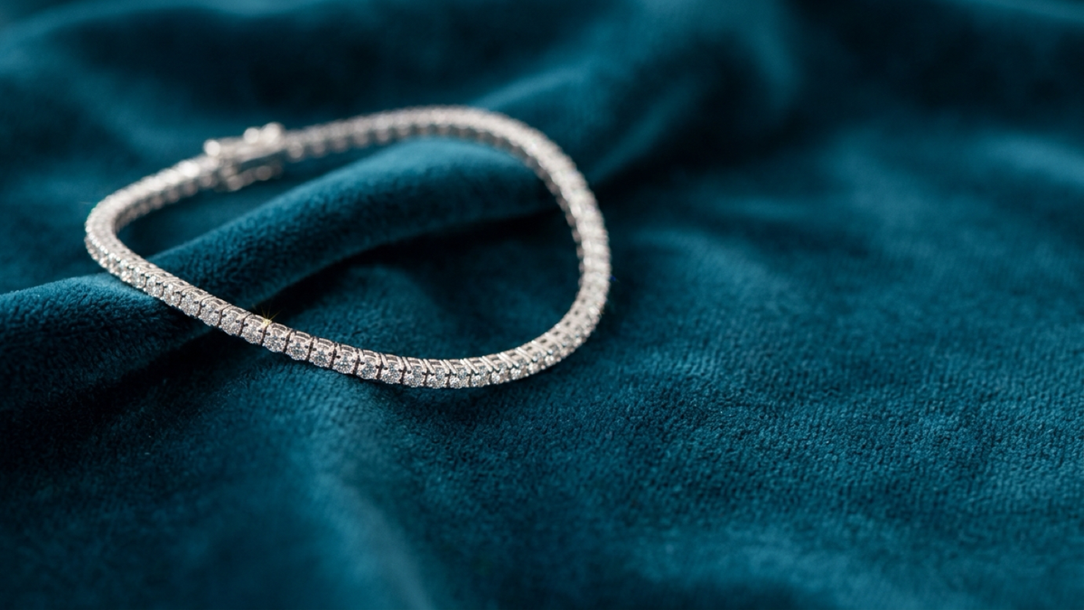 A silver tennis bracelet curved on deep teal velvet