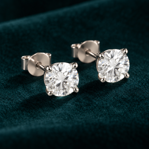 Clemence Stud Earrings: pair of sterling silver four-claw round moissanite studs on teal velvet