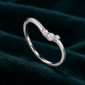 Dione Ring: thin sterling silver V-shaped ring with three small round moissanite stones on teal velvet