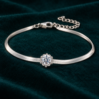Elara Chain Bracelet: slim sterling silver herringbone chain bracelet with a single moissanite centre stone on teal velvet