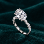 Jessamine Oval Ring: sterling silver oval moissanite solitaire ring with pave shoulders on teal velvet